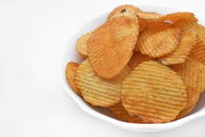 Red pieces of fried potatoes in a plate. Peppery chips on a white background. photo