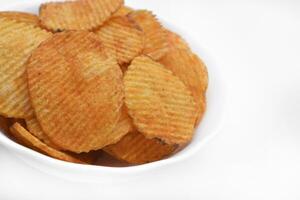 Red pieces of fried potatoes in a plate. Peppery chips on a white background. photo