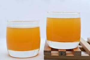 Glass glasses with orange juice on a wooden stand. A soft drink in a glass on a white background. photo