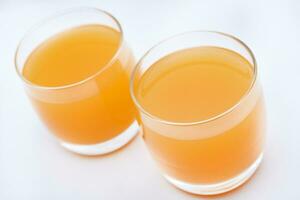 vaso lentes con naranja jugo en un blanco antecedentes. delicioso naranja enfriamiento beber. foto