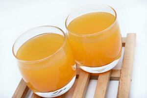 Glass glasses with orange juice on a wooden stand. A soft drink in a glass on a white background. photo