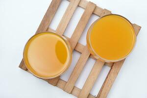 Glass glasses with orange juice on a wooden stand. A soft drink in a glass on a white background. photo