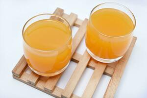 Glass glasses with orange juice on a wooden stand. A soft drink in a glass on a white background. photo