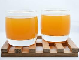 Glass glasses with orange juice on a wooden stand. A soft drink in a glass on a white background. photo