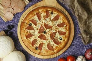 Flatbread pizza garnished with fresh angular on wooden pizza board top view dark stone background photo