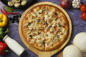 Flatbread pizza garnished with fresh angular on wooden pizza board top view dark stone background photo