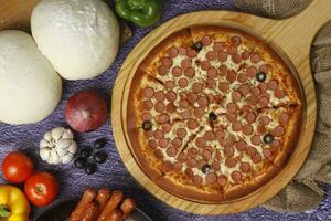 Flatbread pizza garnished with fresh angular on wooden pizza board top view dark stone background photo