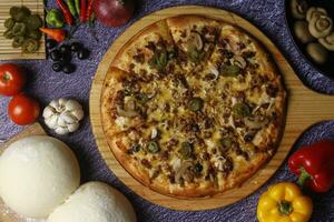 Flatbread pizza garnished with fresh angular on wooden pizza board top view dark stone background photo