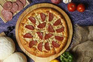 Flatbread pizza garnished with fresh angular on wooden pizza board top view dark stone background photo