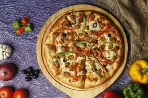 Flatbread pizza garnished with fresh angular on wooden pizza board top view dark stone background photo