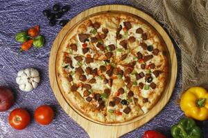 Flatbread pizza garnished with fresh angular on wooden pizza board top view dark stone background photo