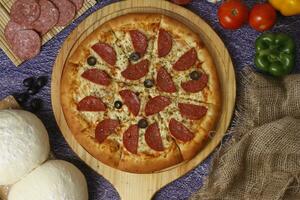 Flatbread pizza garnished with fresh angular on wooden pizza board top view dark stone background photo