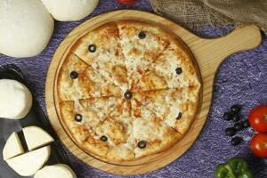 Flatbread pizza garnished with fresh angular on wooden pizza board top view dark stone background photo