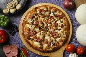 Flatbread pizza garnished with fresh angular on wooden pizza board top view dark stone background photo