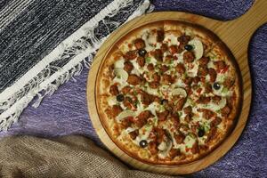 Flatbread pizza garnished with fresh angular on wooden pizza board top view dark stone background photo