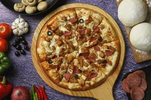 Flatbread pizza garnished with fresh angular on wooden pizza board top view dark stone background photo