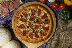 Flatbread pizza garnished with fresh angular on wooden pizza board top view dark stone background photo