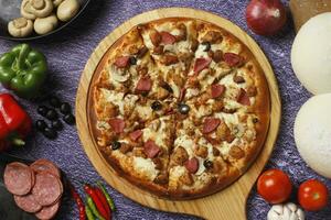 Flatbread pizza garnished with fresh angular on wooden pizza board top view dark stone background photo