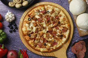 Flatbread pizza garnished with fresh angular on wooden pizza board top view dark stone background photo