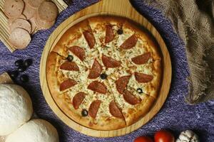 Flatbread pizza garnished with fresh angular on wooden pizza board top view dark stone background photo