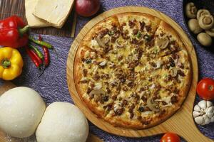 Flatbread pizza garnished with fresh angular on wooden pizza board top view dark stone background photo