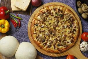Flatbread pizza garnished with fresh angular on wooden pizza board top view dark stone background photo