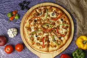 Flatbread pizza garnished with fresh angular on wooden pizza board top view dark stone background photo