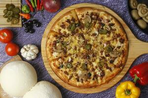 Flatbread pizza garnished with fresh angular on wooden pizza board top view dark stone background photo