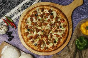 Flatbread pizza garnished with fresh angular on wooden pizza board top view dark stone background photo