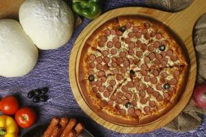 Flatbread pizza garnished with fresh angular on wooden pizza board top view dark stone background photo