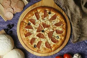 Flatbread pizza garnished with fresh angular on wooden pizza board top view dark stone background photo