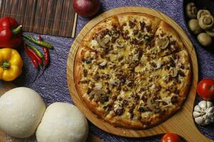 Flatbread pizza garnished with fresh angular on wooden pizza board top view dark stone background photo