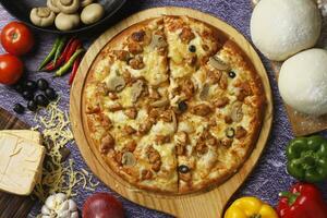 Flatbread pizza garnished with fresh angular on wooden pizza board top view dark stone background photo