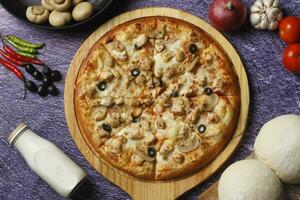 Flatbread pizza garnished with fresh angular on wooden pizza board top view dark stone background photo