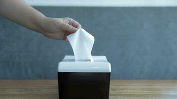 Someone pickup a tissue from a tissue box. A hand pick the tissue or holding a tissue. photo