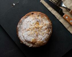 Round pastry with almonds and butter sprinkled with powdered sugar on the table, puff pastry photo