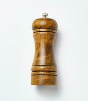 Wooden pepper mill on a white background, made of wood and has a metal handle on top photo