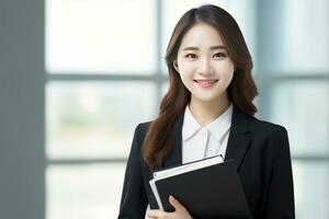 Portrait of Happy Asian Teacher with a Book in School, Young Female Tutor Smiling and Looking at the Camera photo