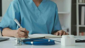 Doctor and patient sitting and talking at medical examination at hospital office, close-up. Therapist filling up medication history records. Medicine and healthcare concept. video