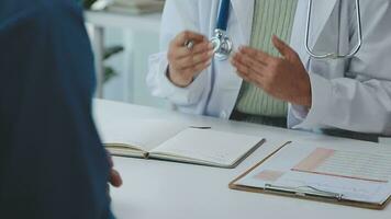 médecin et patient séance et parlant à médical examen à hôpital bureau, fermer. thérapeute remplissage en haut des médicaments histoire enregistrements. médicament et soins de santé concept. video