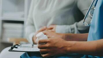 medico e paziente seduta e parlando a medico visita medica a ospedale ufficio, avvicinamento. terapista Riempimento su medicazione storia record. medicina e assistenza sanitaria concetto. video