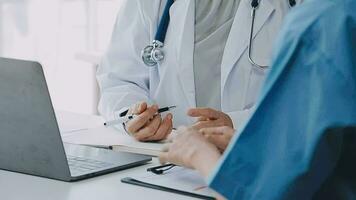 Doctor and patient sitting and talking at medical examination at hospital office, close-up. Therapist filling up medication history records. Medicine and healthcare concept. video