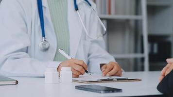 Doctor and patient sitting and talking at medical examination at hospital office, close-up. Therapist filling up medication history records. Medicine and healthcare concept. video