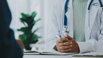 Doctor and patient sitting and talking at medical examination at hospital office, close-up. Therapist filling up medication history records. Medicine and healthcare concept. video