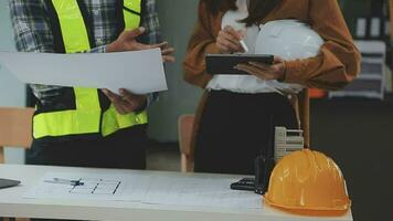 costruzione e struttura concetto di ingegnere o architetto incontro per progetto Lavorando con compagno e ingegneria utensili su modello edificio e planimetria nel Lavorando luogo, contrarre per tutti e due aziende. video