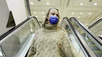 mujer cliente en máscara en escalera mecánica en compras centro comercial video