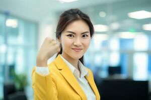 Asian Businesswoman Showing a Fighting Pose, Beautiful Manager Gestures Raising Fists in Modern Office, Female Entrepreneur Fights a Problem, Celebrate Success and Achieving Goals photo