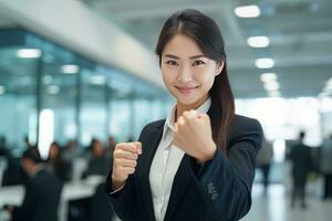 Asian Businesswoman Showing a Fighting Pose, Beautiful Manager Gestures Raising Fists in Modern Office, Female Entrepreneur Fights a Problem, Celebrate Success and Achieving Goals photo