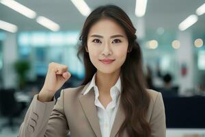 Asian Businesswoman Showing a Fighting Pose, Beautiful Manager Gestures Raising Fists in Modern Office, Female Entrepreneur Fights a Problem, Celebrate Success and Achieving Goals photo