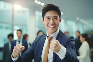 Asian Businessman Showing a Fighting Pose, Male Entrepreneur Gestures Raising Fists in Modern Office, Fights a Problem, Celebrate Success and Achieving Goals. photo